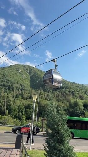 Cable car ascends Almaty's green mountain on a clear day
