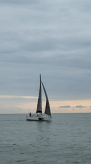 Sailboat cruising calm Batumi waters under a cloudy sky