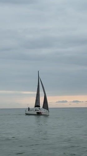 Sailboat cruising calm Batumi waters under a cloudy sky