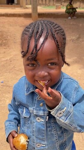 Child photographed eating bread in Nigerian village setting