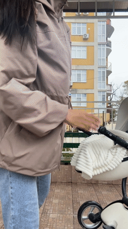 Mother with baby stroller walks covered walkway during rain in Sochi