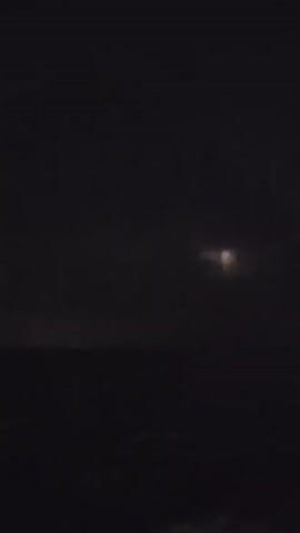 A nighttime video captures lightning striking over a dark body of water. The lightning flashes illuminate the clouds and the surface of the water, creating a dramatic effect. The video appears to be filmed from a stationary position, likely on land or a boat. There are no people or specific objects clearly visible in the frame, other than the natural elements of the storm.