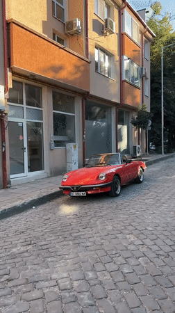 Vintage Alfa Romeo Spider among classic cars on Veliko Tarnovo cobblestones