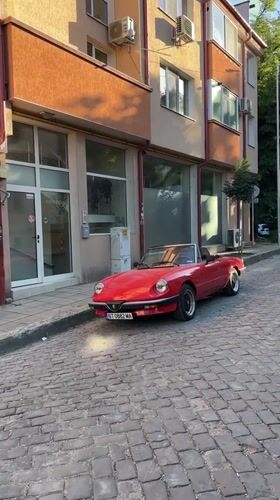 Vintage Alfa Romeo Spider among classic cars on Veliko Tarnovo cobblestones