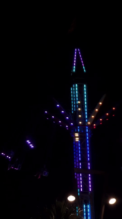 Colorful swing ride spinning at a nighttime carnival in Alghero