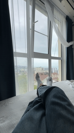 Person rests on bed overlooking Sochi cityscape