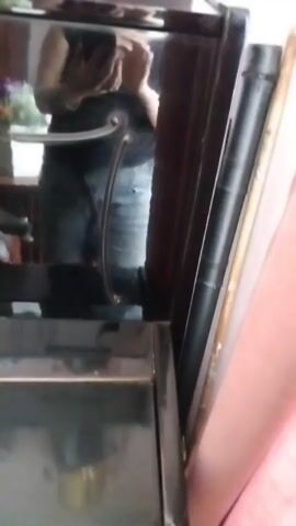 The video shows a trophy with four blue columns on a black surface. Ribbons in red, white, and blue hang from the trophy. The trophy is on top of a black surface that has a mirrored front. There are also other objects visible in the background, including a black tube and a wooden object leaning against a wall. A person's reflection is visible in the mirrored surface of the trophy case.