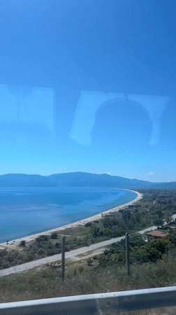 Scenic Greek coastline with sandy beach observed from vehicle