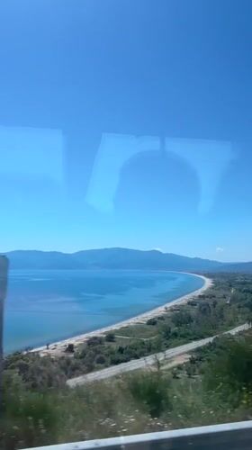 Scenic Greek coastline with sandy beach observed from vehicle