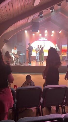Worship band performs under A-frame ceiling with sunset stage backdrop