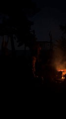 Late-night campfire gathering with drumming and open flames