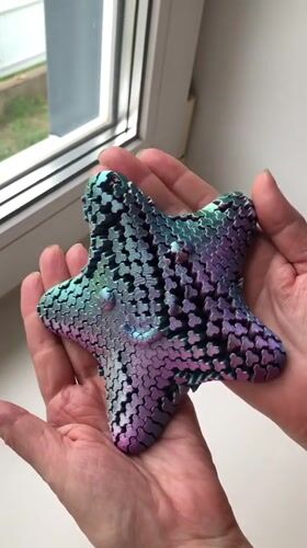 Person holds iridescent star-shaped puzzle object in Noviy, Russia