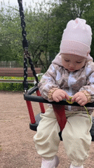 Baby enjoys playground time with dandelion in Pushkin