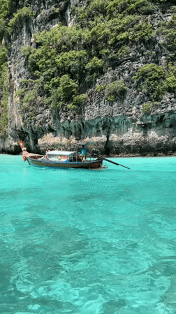 Longtail boat cuts through turquoise water near Ao Nang cliffs