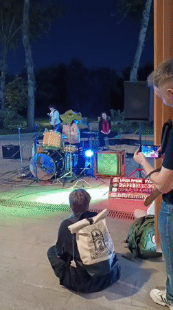 Band performs outdoors in Moscow evening, unrelated cat carrier spotted