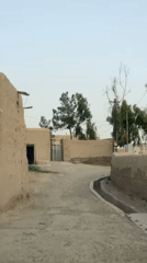 Vehicle drives through rural Kandahar street among traditional buildings