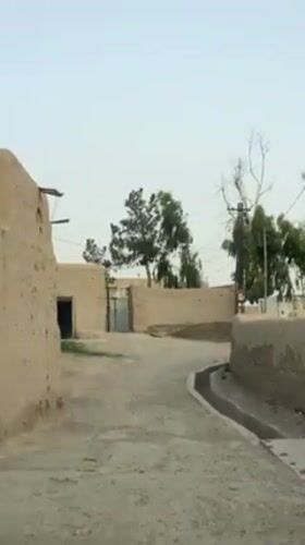 Vehicle drives through rural Kandahar street among traditional buildings