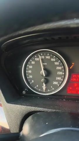 The video shows a close-up of a car's dashboard. The speedometer needle is hovering around 115 km/h, indicating the car is in motion. To the right of the speedometer, a digital display shows the time as 21:19, the outdoor temperature as +26.5 degrees Celsius, and the odometer reading as 225155 km. The car appears to be a diesel model, indicated by the "Diesel" label below the needle. The interior of the car is dimly lit, and the dashboard material is visible in the foreground. The video is shot from the perspective of the driver, looking at the instrument panel.