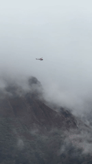 Helicopter navigates dense fog over Nepal mountains near Namche Bazaar
