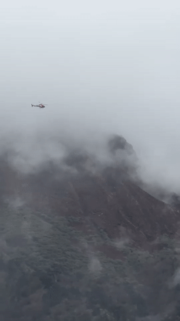 Helicopter navigates dense fog over Nepal mountains near Namche Bazaar
