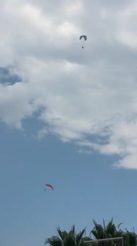 Paragliders soar above Boreti's coastline on a mixed-sky afternoon