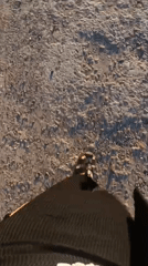 Person in sandals walks on gravel surface