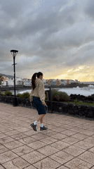 Woman exercises as golden light breaks through clouds in Puerto de la Cruz