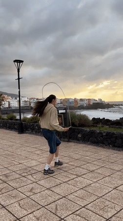 Woman exercises as golden light breaks through clouds in Puerto de la Cruz