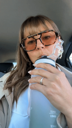 Woman works on laptop while hydrating in car, Antibes