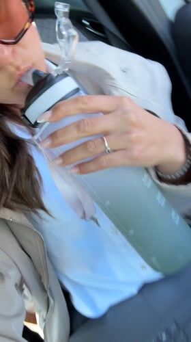 Woman works on laptop while hydrating in car, Antibes