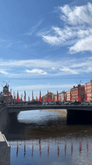 Red flags adorn city bridge over canal during sunny afternoon