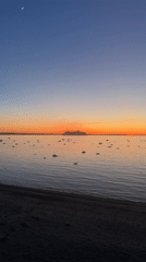 Crescent moon visible over Tallinn beach at dusk