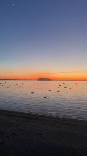 Crescent moon visible over Tallinn beach at dusk