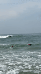 Surfers ride waves at Midigama beach under cloudy skies