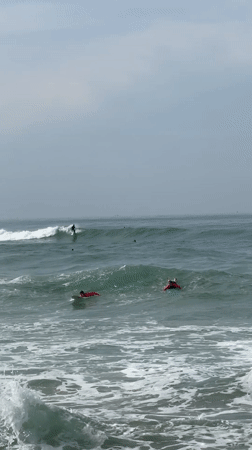 Surfers ride waves at Midigama beach under cloudy skies