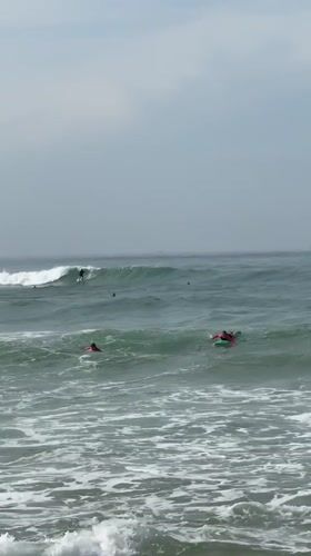 Surfers ride waves at Midigama beach under cloudy skies