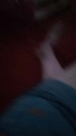 The video is a close-up, shaky shot of a person's leg covered by a blue patterned pajama bottom. The person's skin has several large brownish marks, possibly bruises, visible on their thigh. The lighting is dim, with some bright light at the end of the video possibly from a camera flash. The background is a dark red surface.