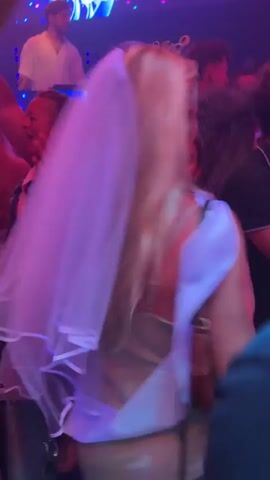 The video shows a crowded, dimly lit nightclub with a DJ booth in the background. The words "DISCO 51" are illuminated above the DJ. People are dancing and raising their arms. One person in the foreground is wearing a white veil, suggesting a bridal party. The lighting is predominantly purple and blue.