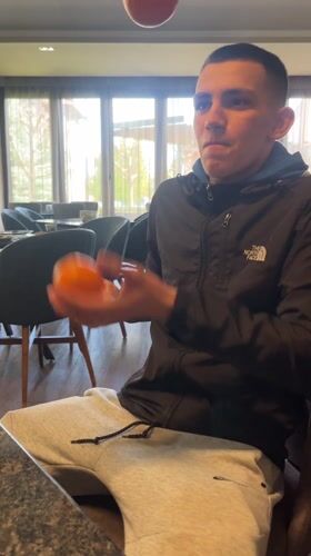Man juggles tangerines in Bulgarian restaurant dining area