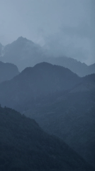 Misty mountains, a river valley, and village rooftops in overcast Vashisht