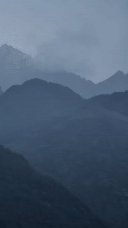 Misty mountains, a river valley, and village rooftops in overcast Vashisht