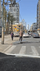 Man rides electric scooter through sunny Tel Aviv streets