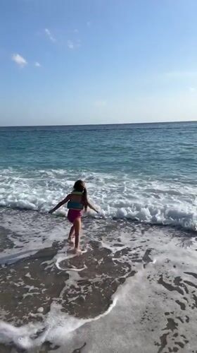 Children play on sunny Fethiye beach, enter turquoise waters