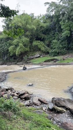Motorcyclist crosses muddy river in Kerambitan, Indonesia