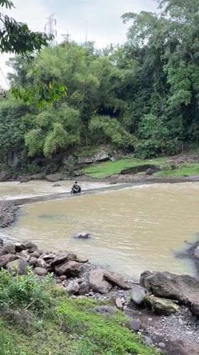 Motorcyclist crosses muddy river in Kerambitan, Indonesia