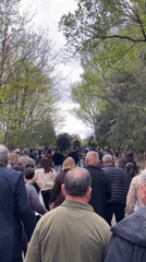 Crowd walks tree-lined path in spring Yerevan