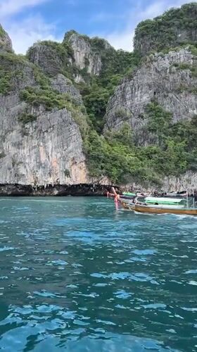 Longtail boats navigate Ao Nang's turquoise waters below limestone cliffs