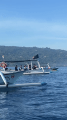 Outrigger boats ferry passengers toward mountain in Banjar waters