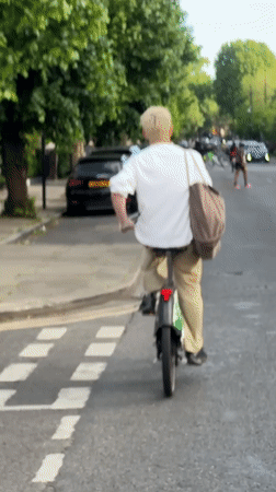 Cyclist rides electric bike through London street