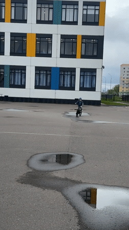 Child cycles through wet streets in Veliky Novgorod